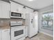 Bright kitchen showcasing white appliances and a sunlit window at 2914 Westmoreland Ct, New Port Richey, FL 34655