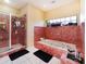 Bright bathroom featuring a shower and a soaking tub with red tiled surround and black mats at 3037 Crest Dr, Clearwater, FL 33759