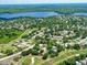 Aerial view of houses, golf course and lakes, surrounded by lush trees and blue skies at 3373 Brodie Way, Palm Harbor, FL 34684