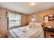 Cozy bedroom with a decorative bedspread, wood paneled walls, and a sunlit window at 36947 Beth Ave, Zephyrhills, FL 33542