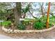 A lush landscaping bed featuring mature trees and flowering plants is framed by a decorative stone border at 36947 Beth Ave, Zephyrhills, FL 33542