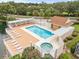 Aerial view of community pool, spa, sunning deck and covered patio surrounded by lush landscaping and lake at 4620 Hidden View Pl # 10, Sarasota, FL 34235