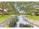 Scenic water view with mature landscaping, fountain and rock lined banks creating a serene community setting at 4620 Hidden View Pl # 10, Sarasota, FL 34235