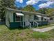 A quaint home with light green siding, dark trim, striped awnings, and a welcoming entryway at 5504 60Th N Way, St Petersburg, FL 33709