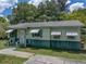 A charming home featuring light green siding, dark green trim, awnings, and a welcoming front entrance with steps at 5504 60Th N Way, St Petersburg, FL 33709