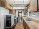 Galley kitchen featuring wood cabinets, white tile backsplash, neutral countertops, and a stainless steel sink at 5504 60Th N Way, St Petersburg, FL 33709