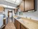 Galley kitchen featuring wood cabinets, white tile backsplash, neutral countertops, and a stainless steel sink at 5504 60Th N Way, St Petersburg, FL 33709