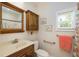 Cozy bathroom featuring a wooden vanity, decorative mirror, and a window with natural light at 6342 5Th N Ave, St Petersburg, FL 33710