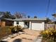 Front exterior showing a charming single-story home featuring a garage and an overgrown lawn at 8361 42Nd N Ave, St Petersburg, FL 33709