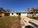 Charming single-story home featuring a garage, tidy lawn, and mature landscaping under a clear blue sky at 8361 42Nd N Ave, St Petersburg, FL 33709