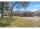 The back of the house features a screened in porch, neutral toned siding, and a spacious backyard at 8449 Valmora St, Spring Hill, FL 34608