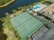 A birds eye view shows meticulously maintained tennis courts with the pool in the background near a lake at 9950 62Nd N Ter # 203, St Petersburg, FL 33708