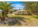 Inviting single-story home with manicured landscaping, a circular driveway, and mature palm trees at 10159 Hernando Ridge Rd, Weeki Wachee, FL 34613