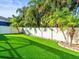 Spacious backyard has lush artificial grass and a privacy fence surrounded by mature palm trees at 10193 Grand Oak Cir, Madeira Beach, FL 33708