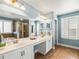 Bright bathroom featuring double sinks, a bathtub, a glass door shower, and blue walls at 10193 Grand Oak Cir, Madeira Beach, FL 33708