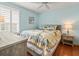 Light blue bedroom with a queen bed, a ceiling fan, a nightstand, and a window dressed with shutters at 10193 Grand Oak Cir, Madeira Beach, FL 33708