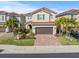 Charming two-story home with a well-manicured lawn, brick driveway, and a red tile roof at 10193 Grand Oak Cir, Madeira Beach, FL 33708