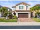 Beautiful two-story home featuring a brick driveway, lush landscaping, and a classic red tile roof at 10193 Grand Oak Cir, Madeira Beach, FL 33708