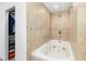 Close up of soaking tub with tan tiling and a shower head, inside the primary bathroom at 10222 95Th St, Seminole, FL 33777