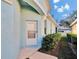 Side exterior of home featuring a white door, light blue siding, and manicured bushes at 11542 Captiva Kay Dr, Riverview, FL 33569