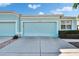 Exterior view of a light blue single story home with a two-car garage and tropical landscaping at 11542 Captiva Kay Dr, Riverview, FL 33569