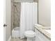 Clean bathroom featuring marble look tile in shower, matching floor, white fixtures and granite vanity at 13526 Alberta Ave, Port Charlotte, FL 33981