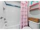 Bright bathroom featuring white tile, pink shower curtain and decorative pink shelving at 18329 Roseate Dr, Lutz, FL 33558