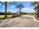 Stone entrance to 'Primrose Estates' under blue skies, framed by palm trees and manicured landscaping at 18329 Roseate Dr, Lutz, FL 33558