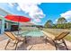 Inviting backyard pool with brick paver decking, red umbrella, lounge chairs and pristine landscaping at 18329 Roseate Dr, Lutz, FL 33558