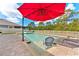 Inviting backyard pool with brick paver decking, red umbrella, lounge chairs and pristine landscaping at 18329 Roseate Dr, Lutz, FL 33558