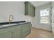 Stylish laundry room with green cabinets, black countertop, gold faucet, and window at 243 28Th N Ave, St Petersburg, FL 33704