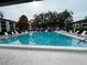 Large community pool with lounge chairs and mature trees at 2591 Countryside Blvd # 5203, Clearwater, FL 33761