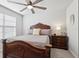 Bedroom features an ornate wood bed frame, ceiling fan, and side table at 25993 Woven Wicker Bnd, Lutz, FL 33559