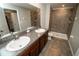 Bathroom featuring a double sink vanity with granite counter and tiled walk-in shower at 3808 Cat Mint St, Tampa, FL 33619