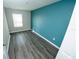 A bedroom with gray plank flooring, a light wall, and a blue accent wall at 3808 Cat Mint St, Tampa, FL 33619