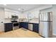 Well lit kitchen with stainless steel appliances and two-tone navy and white cabinets at 39035 Citadel Cir, Zephyrhills, FL 33542