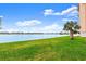 Scenic waterfront view with lush green lawn, palm tree, and heron in the distance at 500 Treasure Island Cswy # 404, Treasure Island, FL 33706