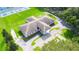 Aerial view of a clubhouse surrounded by a green lawn, trees, a parking lot, and tennis courts in the background at 5238 Mary St, Zephyrhills, FL 33542