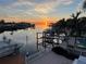 Scenic waterfront view at sunset with boat dock, boats, calm waters, and lush palm trees at 567 Baywood S Dr, Dunedin, FL 34698