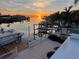 Waterfront views featuring docks and a boat lift at sunset at 567 Baywood S Dr, Dunedin, FL 34698