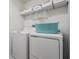 Functional laundry room with white washer and dryer, plus storage shelves at 6256 Shiner St, Land O Lakes, FL 34638