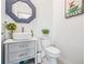 Stylish powder room with a vessel sink, gray vanity, striped mirror and quirky wall art at 6256 Shiner St, Land O Lakes, FL 34638