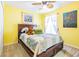 Bedroom features a bed, ceiling fan, and colorful paintings on bright yellow walls at 7301 Avocet Dr, Wesley Chapel, FL 33544