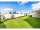 Expansive backyard with lush artificial grass, a white fence, and manicured landscaping at 7324 Steer Blade Dr, Zephyrhills, FL 33541