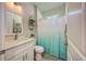 Bathroom with white vanity, toilet, and tub/shower combo with white and blue curtain at 817 Wilkie St, Dunedin, FL 34698