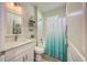 Bathroom with white vanity, toilet, and tub/shower combo with white and blue curtain at 817 Wilkie St, Dunedin, FL 34698