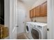 Well-equipped laundry room includes a side by side washer and dryer and wooden cabinets for convenient storage at 833 Seminole Sky Dr, Ruskin, FL 33570