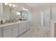 Light and airy bathroom with double vanity, tiled floors, and view into adjacent rooms at 9273 Highland Hills Dr, Hudson, FL 34667