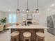 Open-concept kitchen with an island, pendant lighting, white cabinetry, and stainless steel appliances at 9273 Highland Hills Dr, Hudson, FL 34667