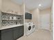 Well-lit laundry room featuring modern washer and dryer units, shelving, sink, and tile backsplash at 9273 Highland Hills Dr, Hudson, FL 34667